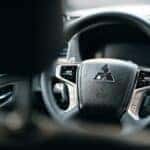 A black steering wheel of a Mitsubishi car taken from the back seat