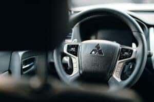 A black steering wheel of a Mitsubishi car taken from the back seat