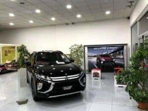 A black Mitsubishi in the showroom next to a poster advertising the Eclipse Cross