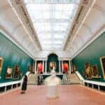 A woman walking through a museum looking at all the artwork around her