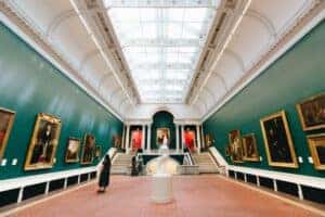 A woman walking through a museum looking at all the artwork around her
