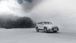 A white Mitsubishi in a snowstorm in the woods