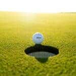 A golf ball about to roll into the hole during a round of golf
