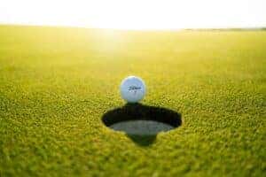 A golf ball about to roll into the hole during a round of golf
