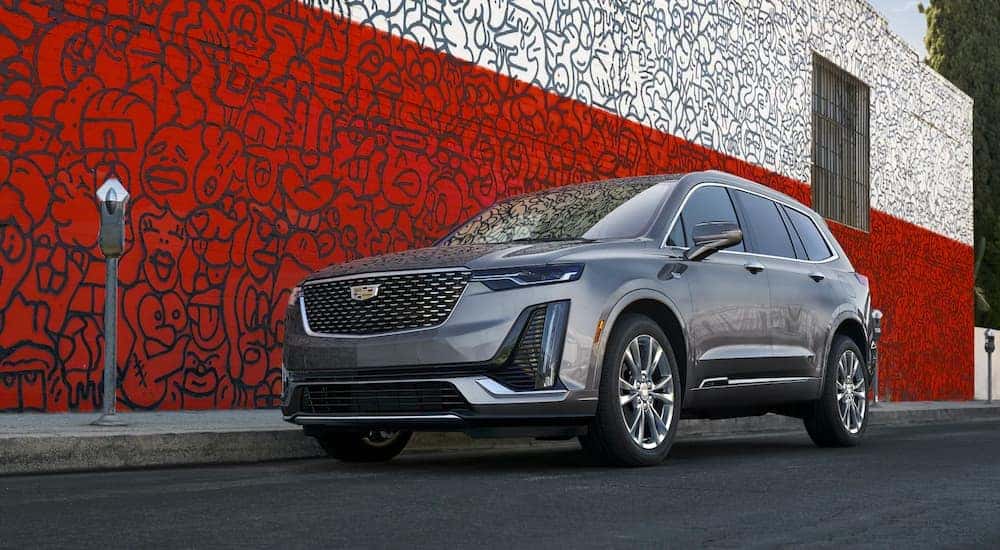 Grey 2022 Cadillac XT6 parked on the side of the street next to a mural