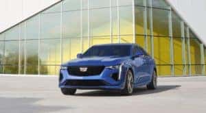 Front view of a blue 2021 Cadillac CT4-V parked in front of a large modern building