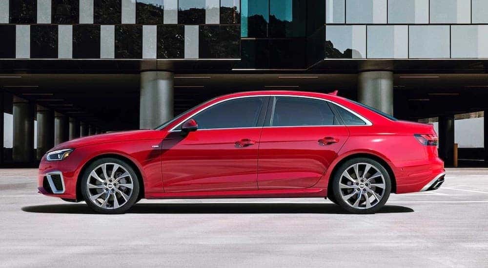 Side view of a red 2022 Audi A4 parked in front of a glass building