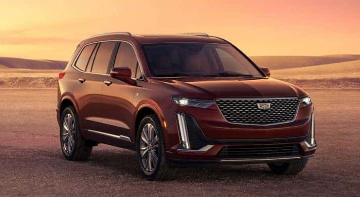 A red 2023 Cadillac XT6, a popular Cadillac SUV for sale, is shown parked during a sunset overlooking a desert.