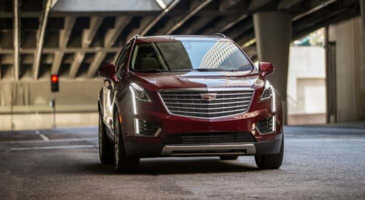 A maroon 2017 used Cadillac XT5 for sale is shown driving on a city street.