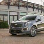A grey used 2020 Cadillac XT5 Premium for sale is shown parked next to a car dealership.