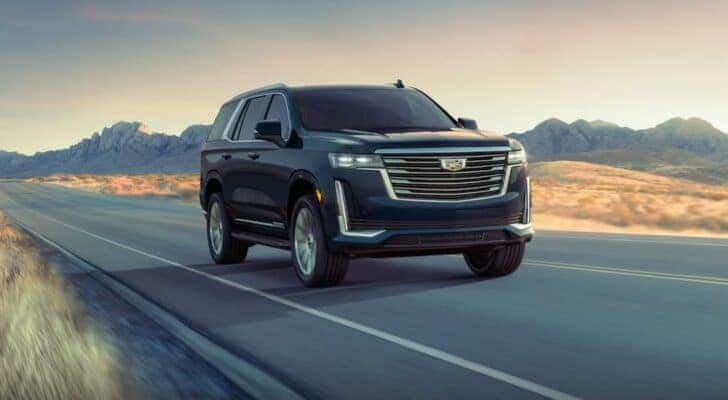 A black 2023 Cadillac Escalade is shown driving on an open road.