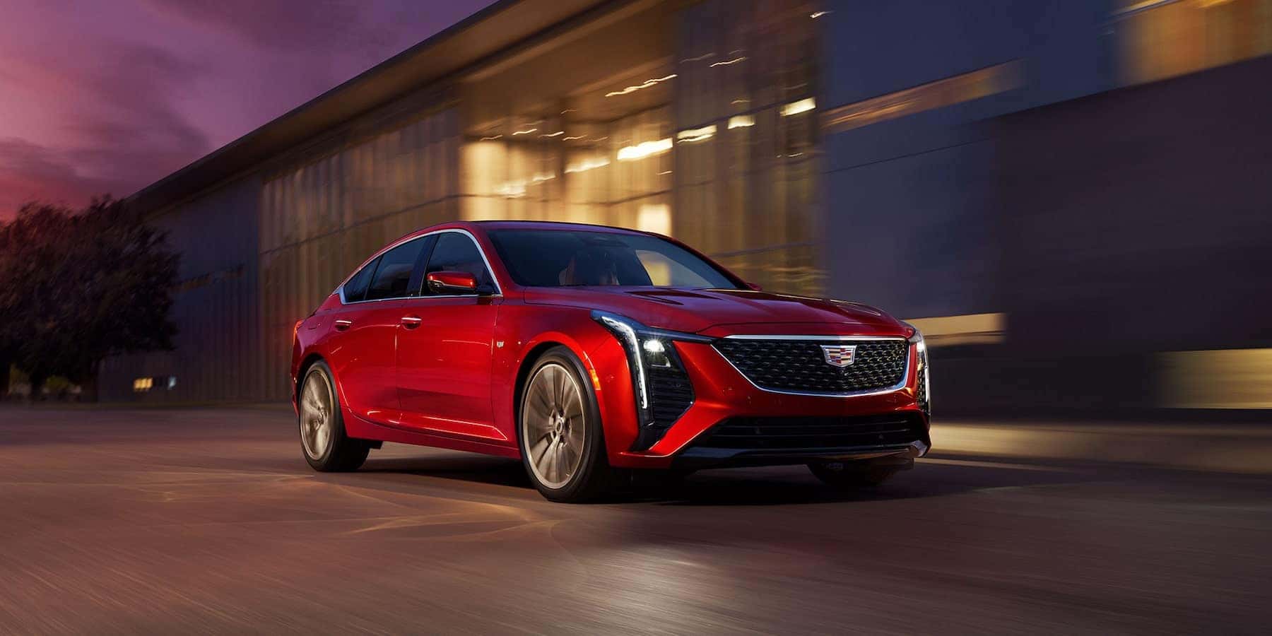 A red 2025 Cadillac VT5 driving down a road