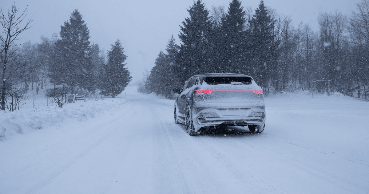 A vehicle driving down a snowy road while it's snowing