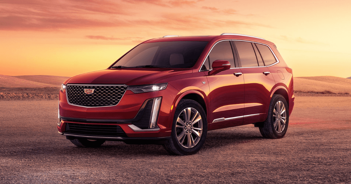 A red 2025 Cadillac XT6 parked in a flat area while the sun sets