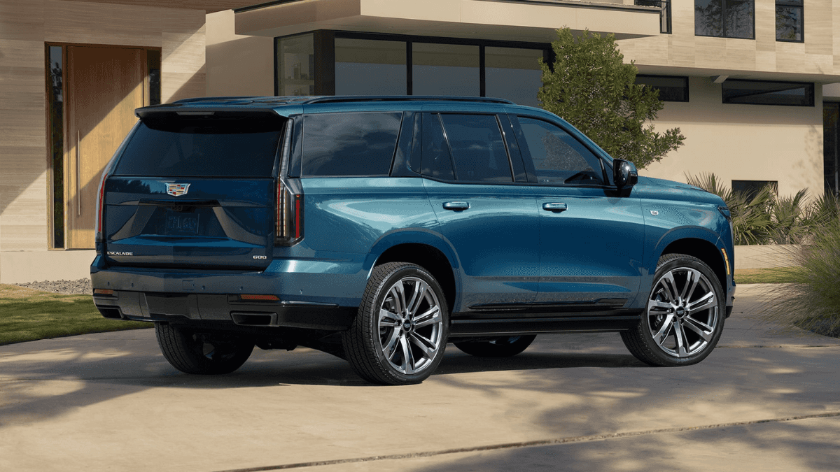 A side view of a blue 2025 Cadillac Escalade parked in front of a house