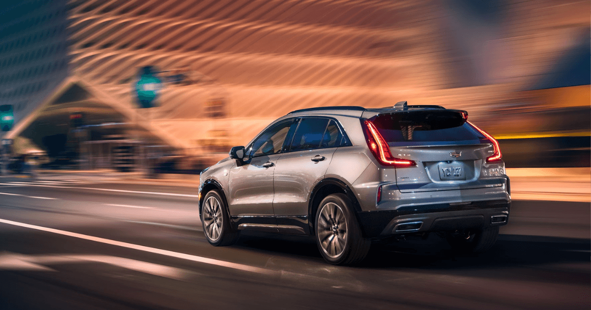 A silver Cadillac XT4 driving quickly down the road in a city