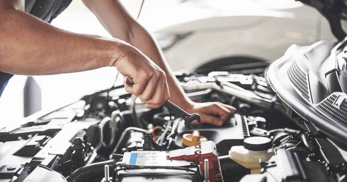 A technician performing engine maintenance on a vehicle