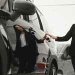 A salesperson examining a black, luxury SUV inside a dealership