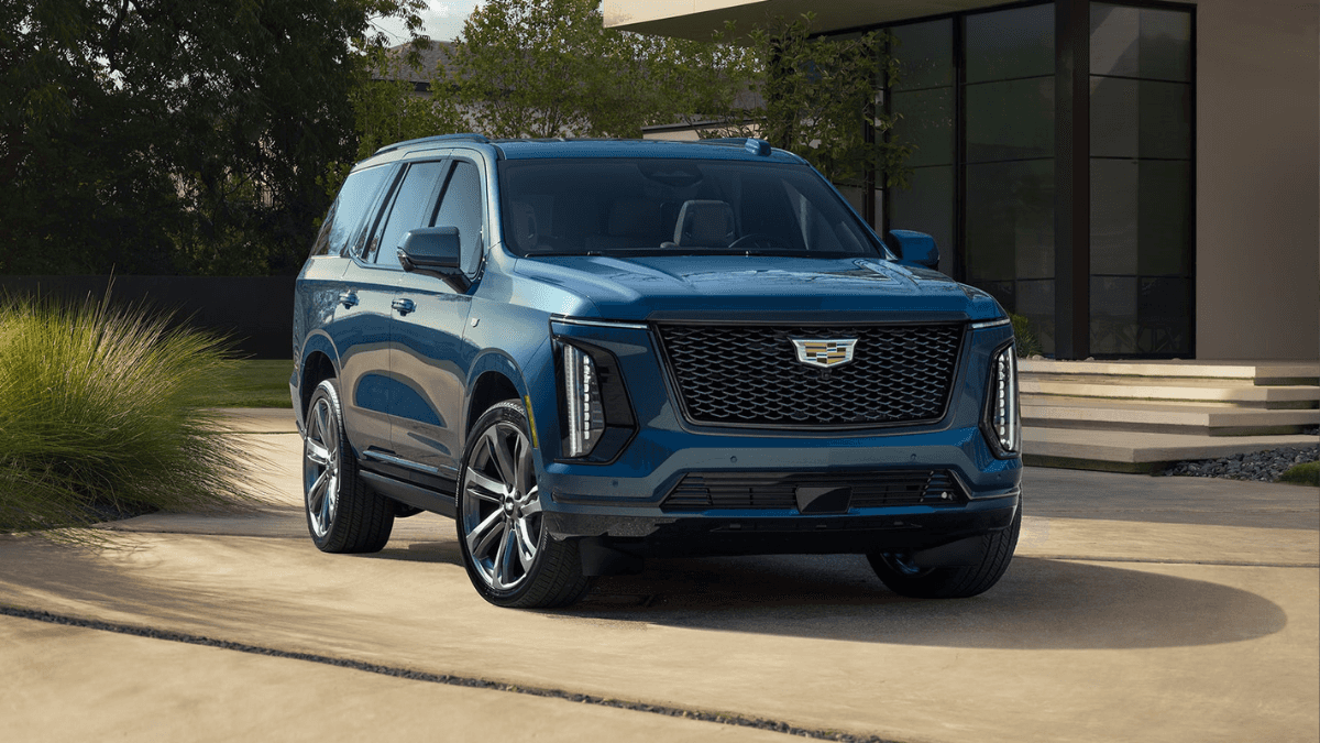 A blue Cadillac Escalade parked outside of a nice house