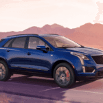 A blue Cadillac XT5 driving down the road through a desert