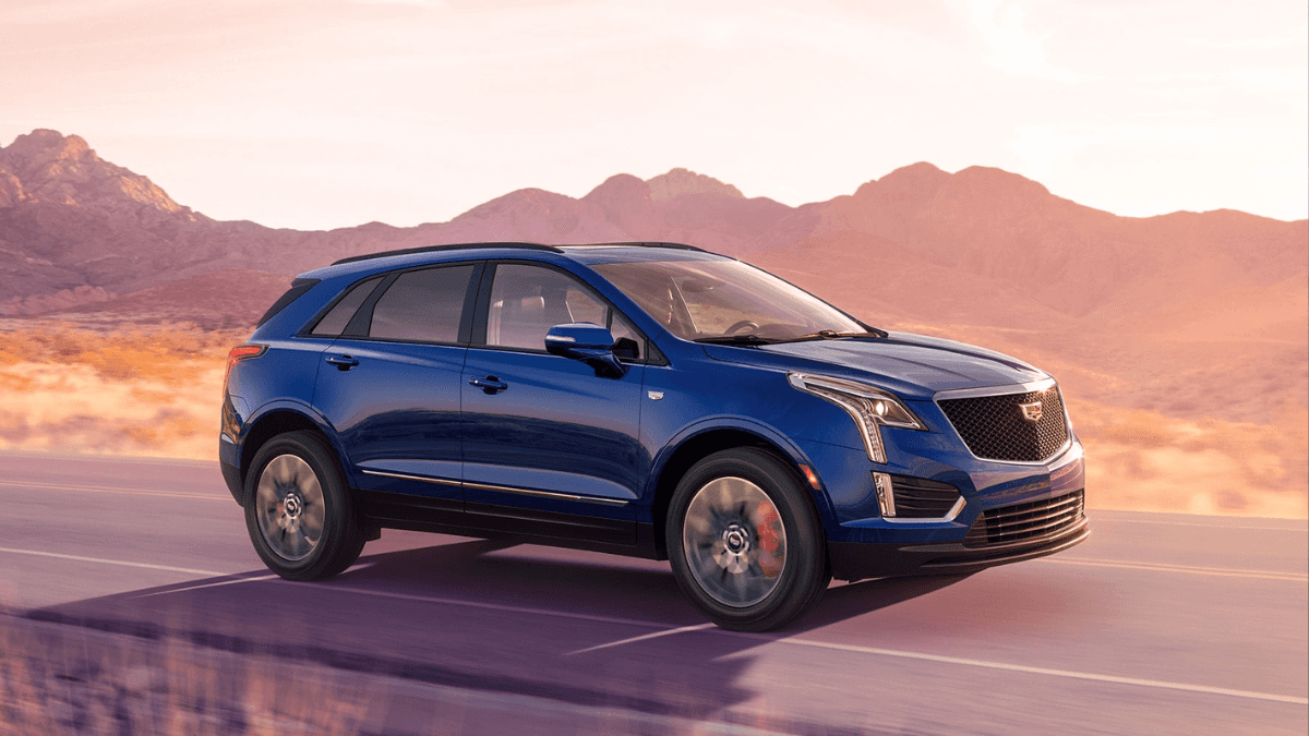 A blue Cadillac XT5 driving down the road through a desert