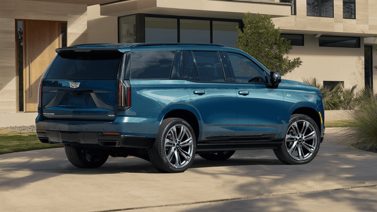 A blue Cadillac Escalade parked outside of a nice house