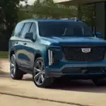 A blue Cadillac Escalade parked in front of a nice house