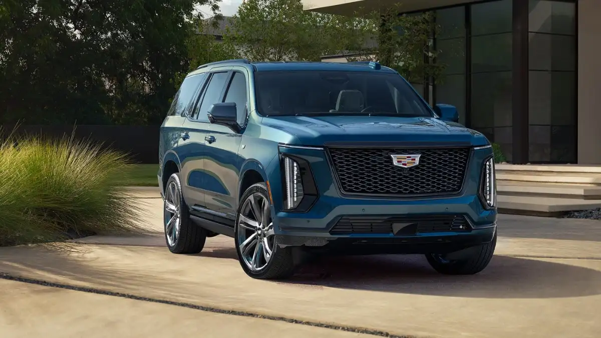 A blue Cadillac Escalade parked in front of a nice house