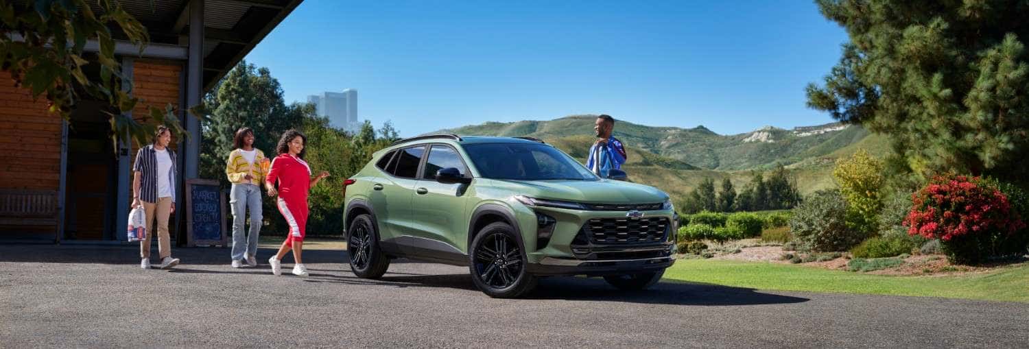 2026 Chevrolet Trax parked outside a building with scenic mountain views in St. George, UT, as people walk nearby.