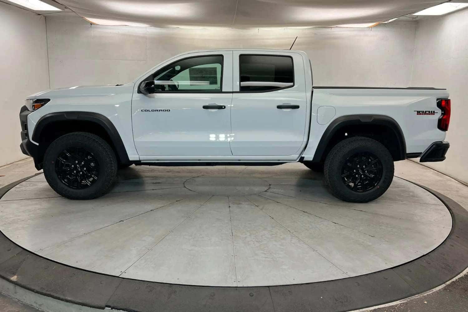Side view of a white 2027 Chevy Colorado pickup truck displayed on a rotating platform in St. George, UT
