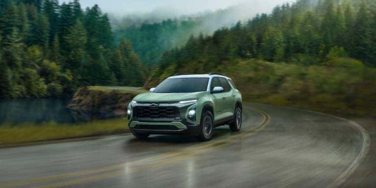 2026 Chevy Equinox SUV navigating a winding road surrounded by trees and a lakeside landscape in St. George, UT