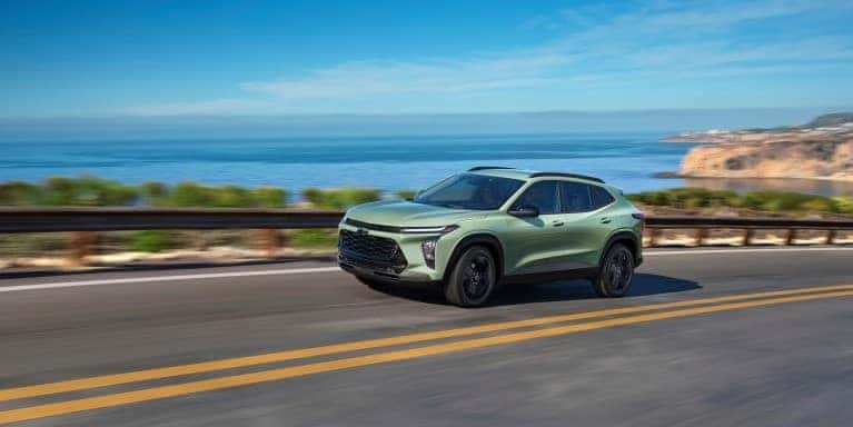 2026 Chevy Trax compact SUV driving along a scenic coastal highway with ocean views and rugged cliffs in St. George, UT