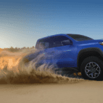 a blue 2026 Chevy Colorado in a sand dune with sand spraying from the back tires