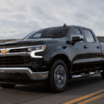 A 2026 Chevrolet Silverado 1500 driving on a main road with 2 cactus on the far left