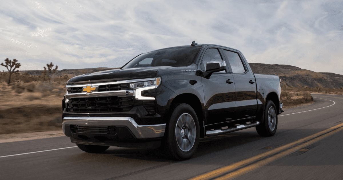 A 2026 Chevrolet Silverado 1500 driving on a main road with 2 cactus on the far left