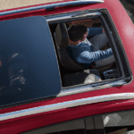 A red Chevy Equinox with the sunroof open while driving