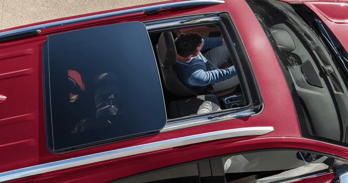 A red Chevy Equinox with the sunroof open while driving