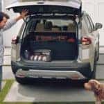 A man and his dog loading up the back of a 2021 Nissan Rogue parked in residential driveway_mobile